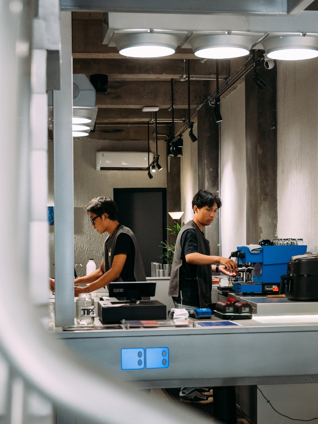 Two Burabura baristas working behind the counter beside a blue espresso machine