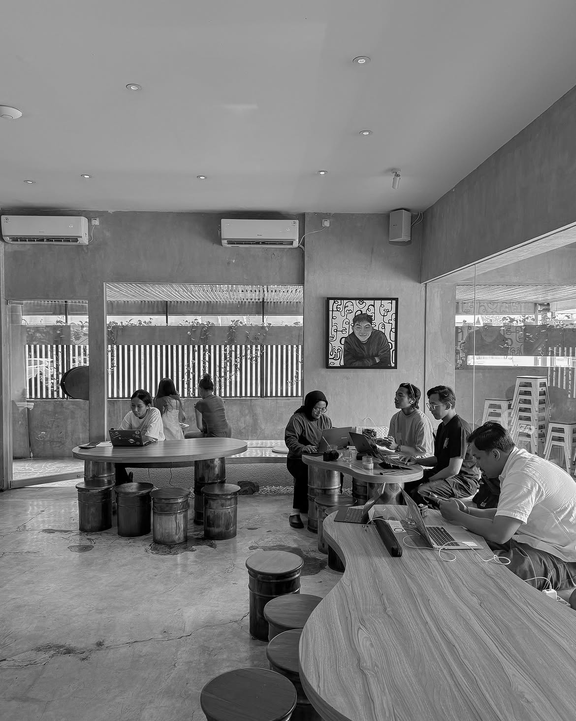 Guests talking and working around shared tables in the Burabura café